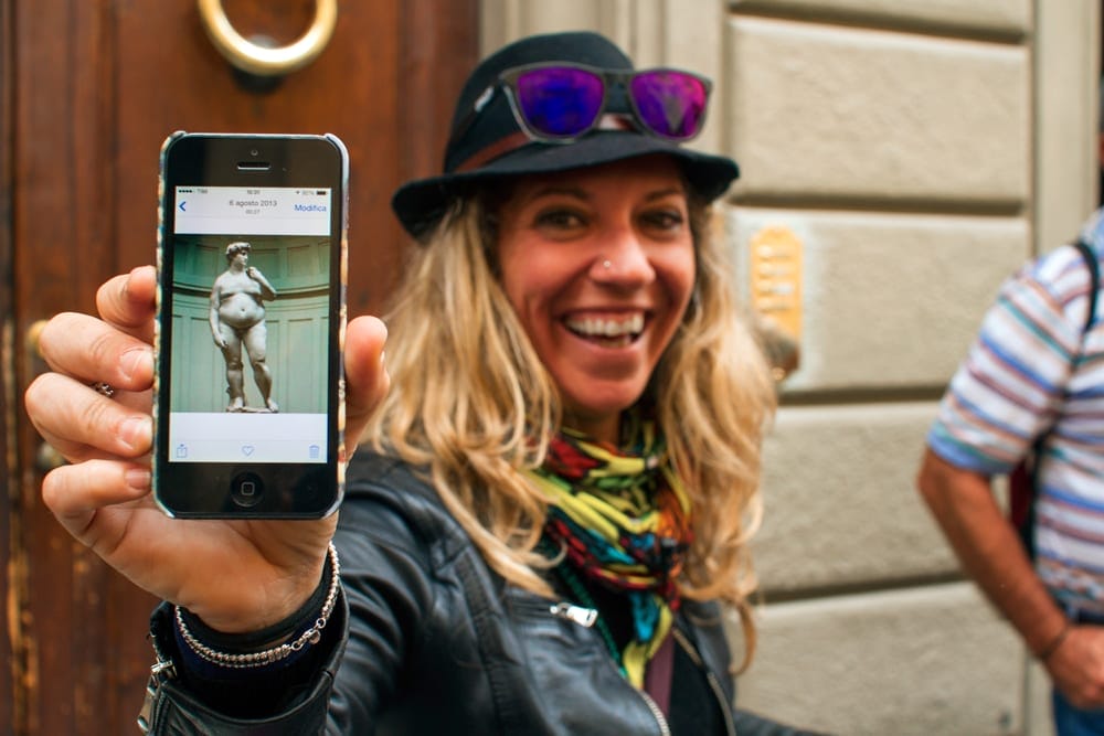 A Walks of Itay guide poses with her camera-phone-picture of Michelangelo's David. 