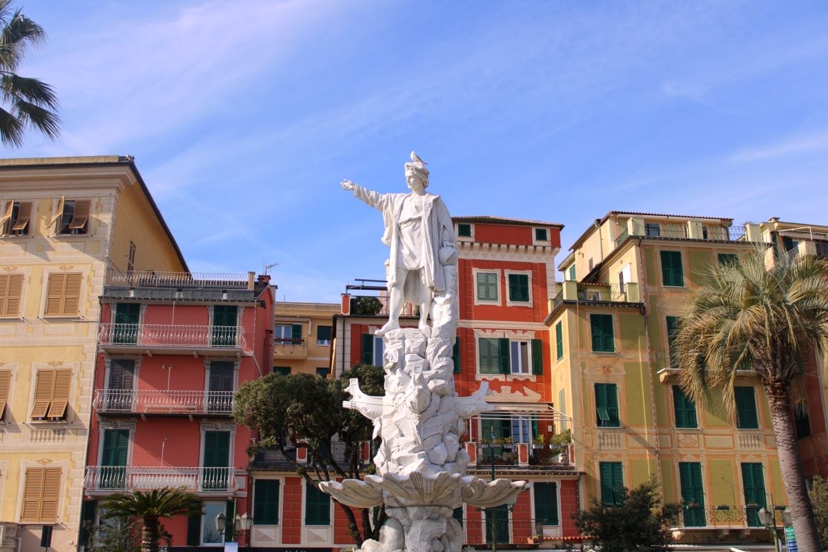 Closeup of statue with colorful buildings in the background.