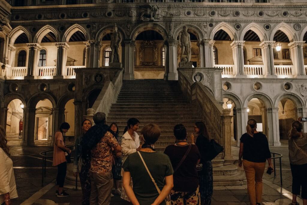 Doge's Palace courtyard in Venice with group of visitors after dark
