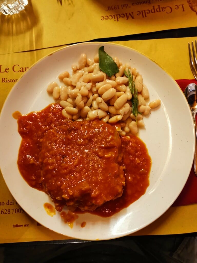 Ossobuco with tomatoes served on a plate with white beans at a restaurant.