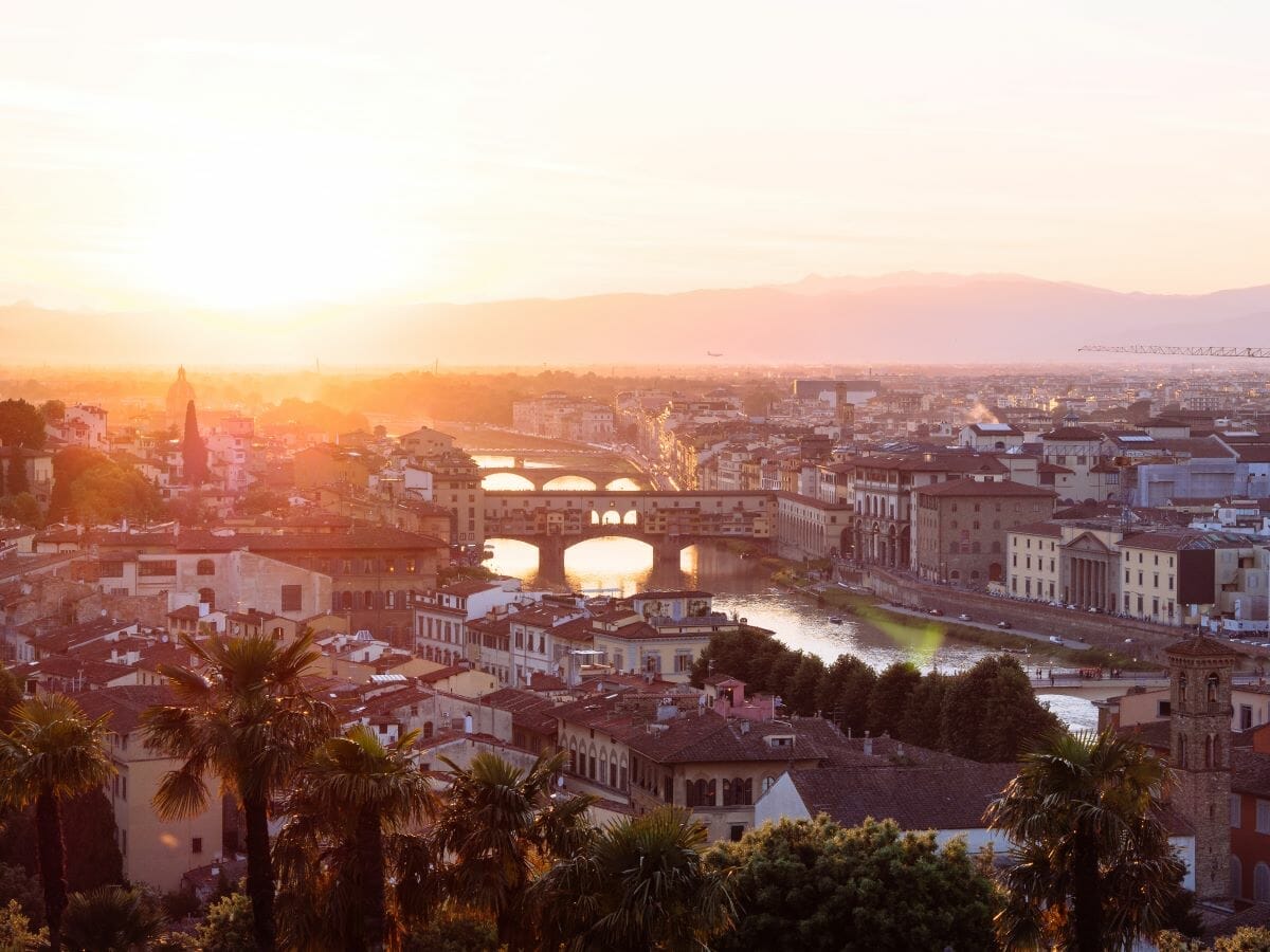 An aerial view of Florence at sunset with views of buildings and the river